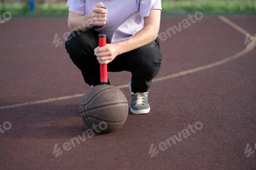 Preview: a person holding a red hand pump and basketball ball