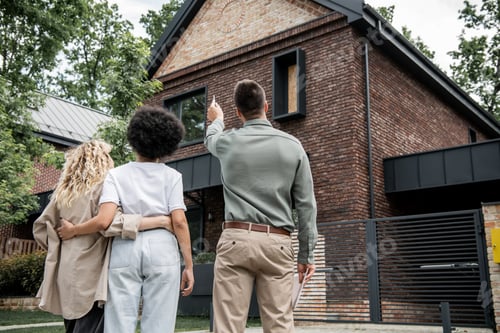 Preview: back view of real estate broker showing new cottage to interracial lesbian couple outdoors