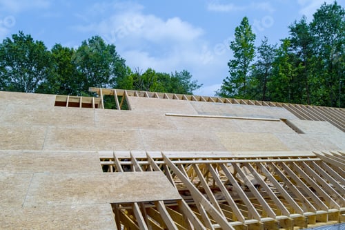 Preview: An under construction wooden home is being constructed on top of roof beams a construction site