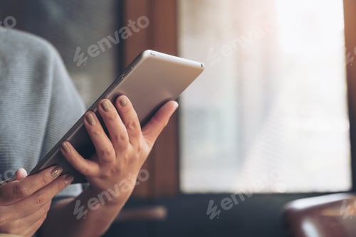 Preview: A woman's hands holding and using tablet pc in cafe