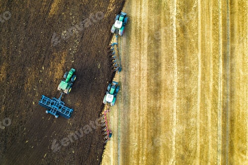 Preview: Aerial view of a tractor plowing black agriculture farm field after harvesting in late autumn.