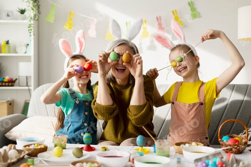 Preview: Happy grandmother and granddaughters playing with easter eggs