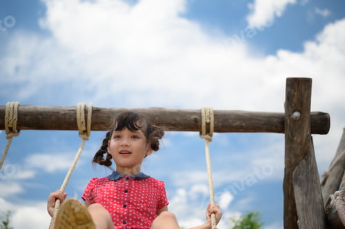 Preview: A little girl having fun swinging on a swing on a clear day