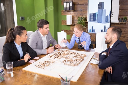 Preview: Real estate developer in business suit in a meeing with team of architects