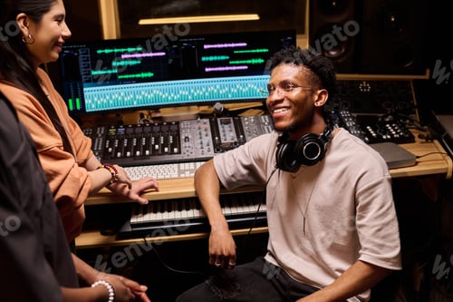Preview: Young Black Man Smiling While Collaborating with Colleagues in Recording Studio