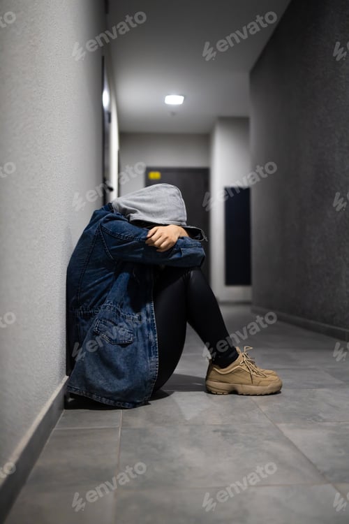 Preview: A depressed teenage girl sits alone on the floor in a dark room.