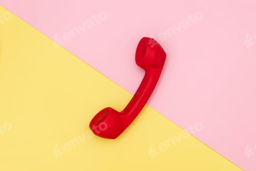 Preview: Red handset of dial phone on yellow and pink backgrounds.