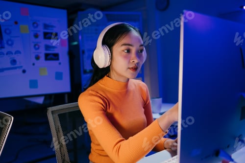 Preview: Young professional focused on her tasks, working overtime in a modern office