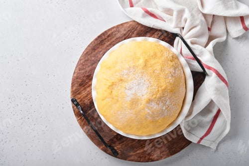 Preview: Raw yeast dough with pumpkin in white bowl covered with towel on the floured kitchen table, recipe i