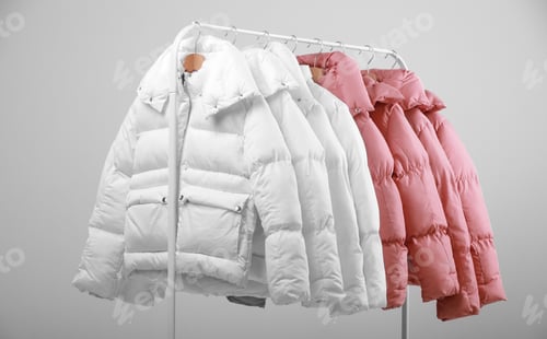 Preview: collection of stylish white and soft pink colours warm jackets hanging on wooden clothes hanger on