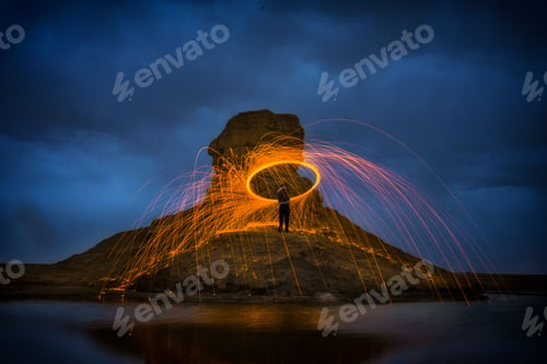 Preview: Man standing in a nighttime scene, illuminated by the long exposure swirls around him