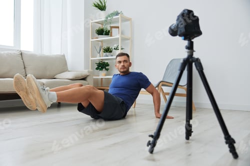 Preview: Man athlete blogger records exercise training on the body at home on camera, sports blogger