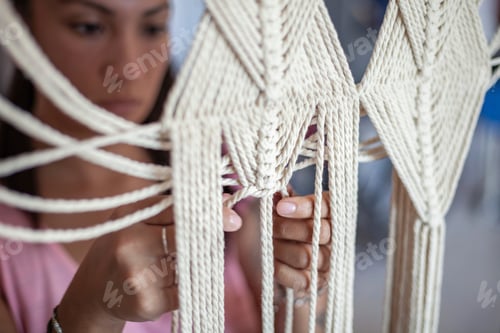 Preview: Focused craftsperson intricately working on a macrame project.
