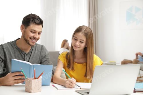 Preview: Father helping his teenager daughter with homework indoors