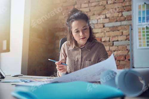 Preview: Busy female interior designer working with drawing, material sample in her office