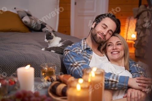 Preview: Happy couple hugging on floor near bed with cat