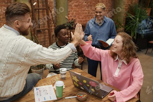 Preview: Group of Young People High Five Across Meeting Table