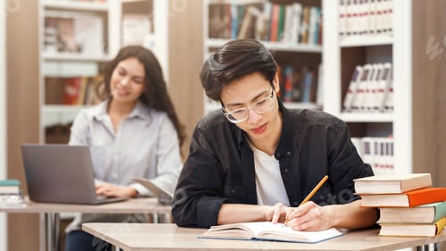 Preview: Asian guy doing research sitting at desk in library