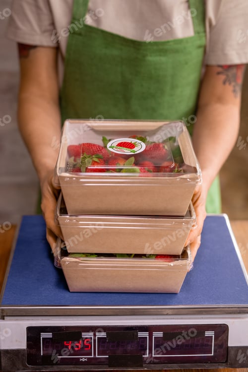 Preview: Hands of young vertical farm worker holding stack of containers with fresh ripe strawberries