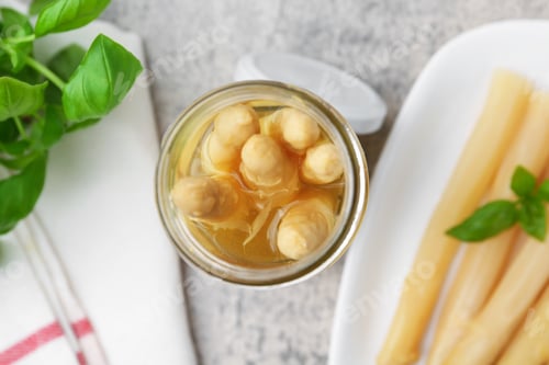 Preview: Pickled asparagus and basil on light grey table, flat lay
