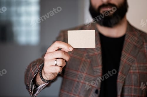 Preview: Bearded businessman holding hand empty white business card on blurred background.