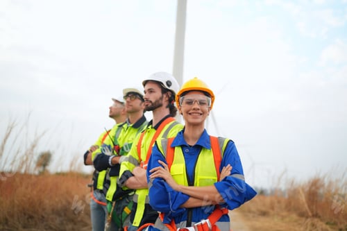 Preview: Wide perspective of wind turbine engineers walking with coworker in wind farms