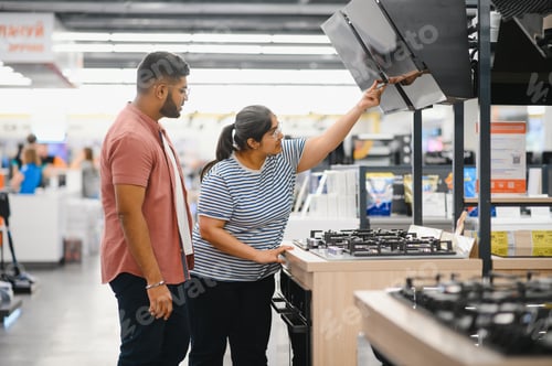 Preview: Young indian couple choosing new gas stove in home appliances store
