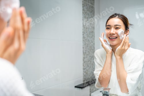 Preview: Asian beautiful woman washing her clean face with facial foam and water.