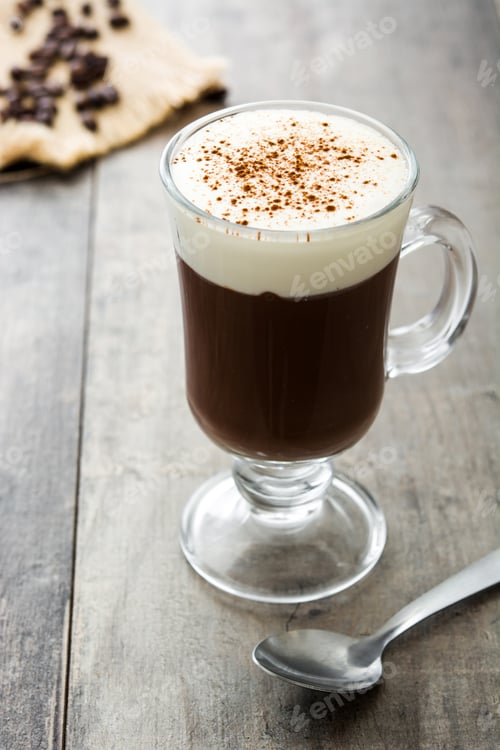 Preview: Hot chocolate with whipped cream and cinnamon in irish coffee glass on rustic wooden table