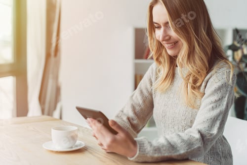 Preview: cheerful woman studing with ebook near cup of tea at home