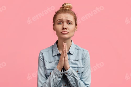 Preview: Do favour for me, please! Beautiful blonde female clasps hands together, makes praying gesture and l