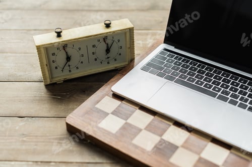 Preview: Chess clock, laptop and chess board on rustic wooden surface
