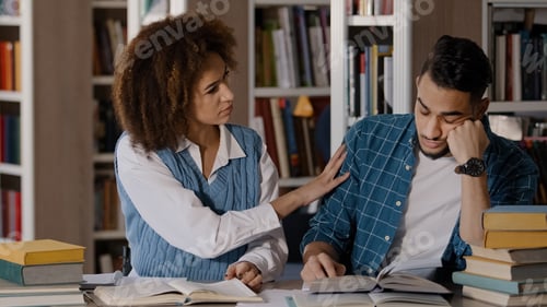 Preview: Two students guy and girl sitting at desk classroom writes notes in notebook writing information