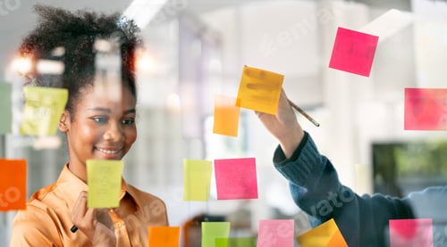 Preview: Young businesswoman using sticky notes in glass wall to writing strategy business plan to success.