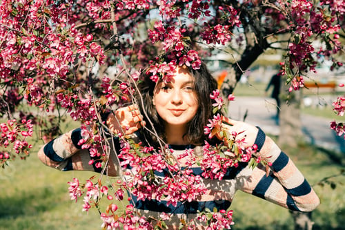 Preview: Beautiful happy young woman enjoying smell in a flowering spring garden