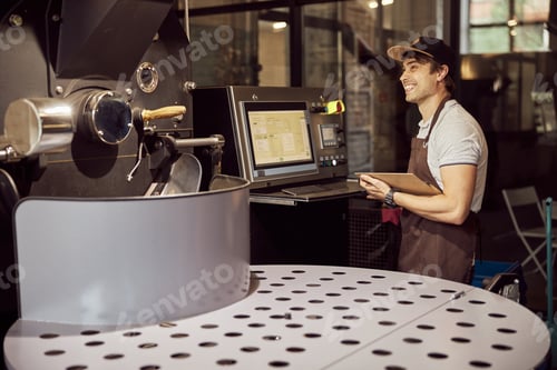 Preview: Cheerful young man using coffee roasting machine