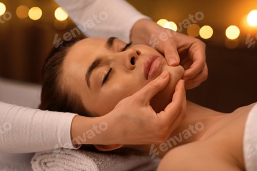 Preview: Relaxed woman getting healing face massage at spa