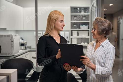 Preview: Clinic administrator consults elderly lady in dental clinic