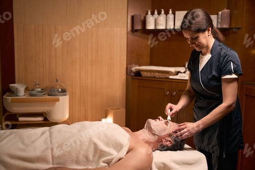 Preview: Qualified cosmetician performing anti-aging treatment on mature man face