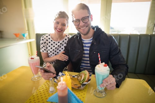 Preview: Couple using mobile phone in restaurant