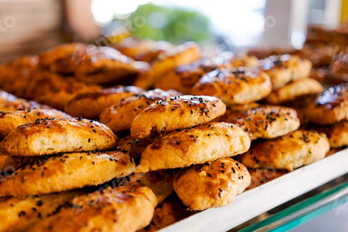 Preview: Freshly baked pastries with black sesame seeds on a tray.