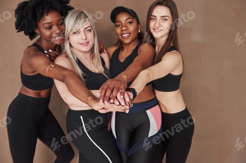 Preview: Group of multi ethnic women standing in the studio against brown background