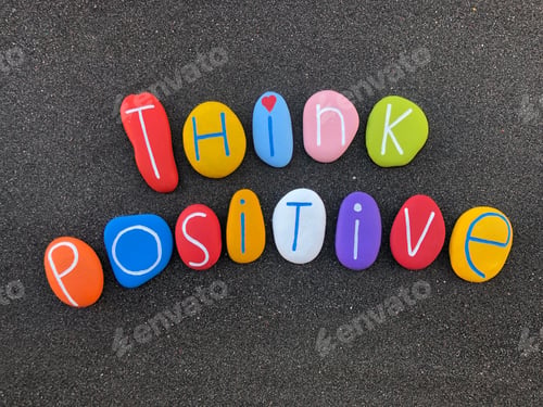 Preview: Think positive text composed with multicolored stone letters over volcanic sand