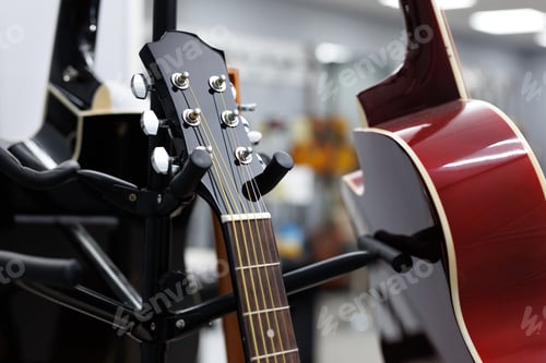 Preview: Close-up of the fingerboard of wooden guitars, ukulele on a guitar stand in the hall of music store.