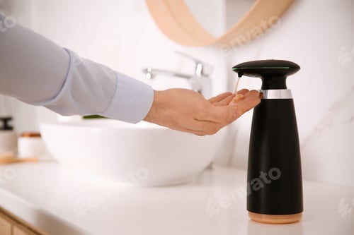 Preview: Man using automatic soap dispenser in bathroom, closeup