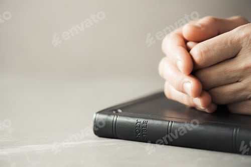 Hands closed in prayer on Holy Bible. Christian banner with copy space. Prayer and gospel spreading