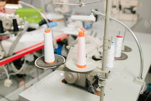 Preview: Thread spools stand on table, organized for garment and apparel production.