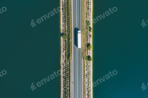 Preview: Aerial drone view of large freight transporter semi-truck driving on the bridge road over blue sea