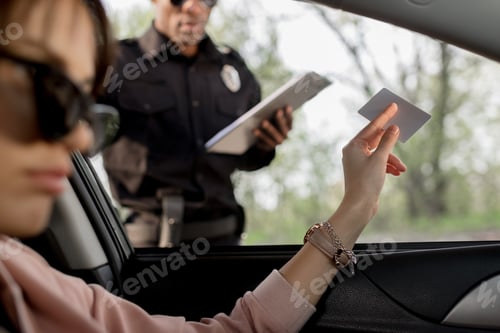 Preview: woman in sunglasses sitting in car and giving driver license to policeman
