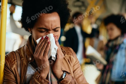 Preview: African American woman blowing nose while traveling by public transport.